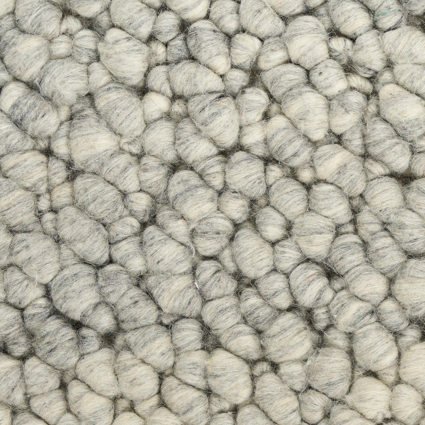 Close-up of chunky gray boucle rug fibers; soft, woolly loops in light to medium gray.