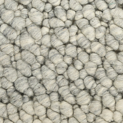 Close-up of chunky gray boucle rug fibers; soft, woolly loops in light to medium gray.