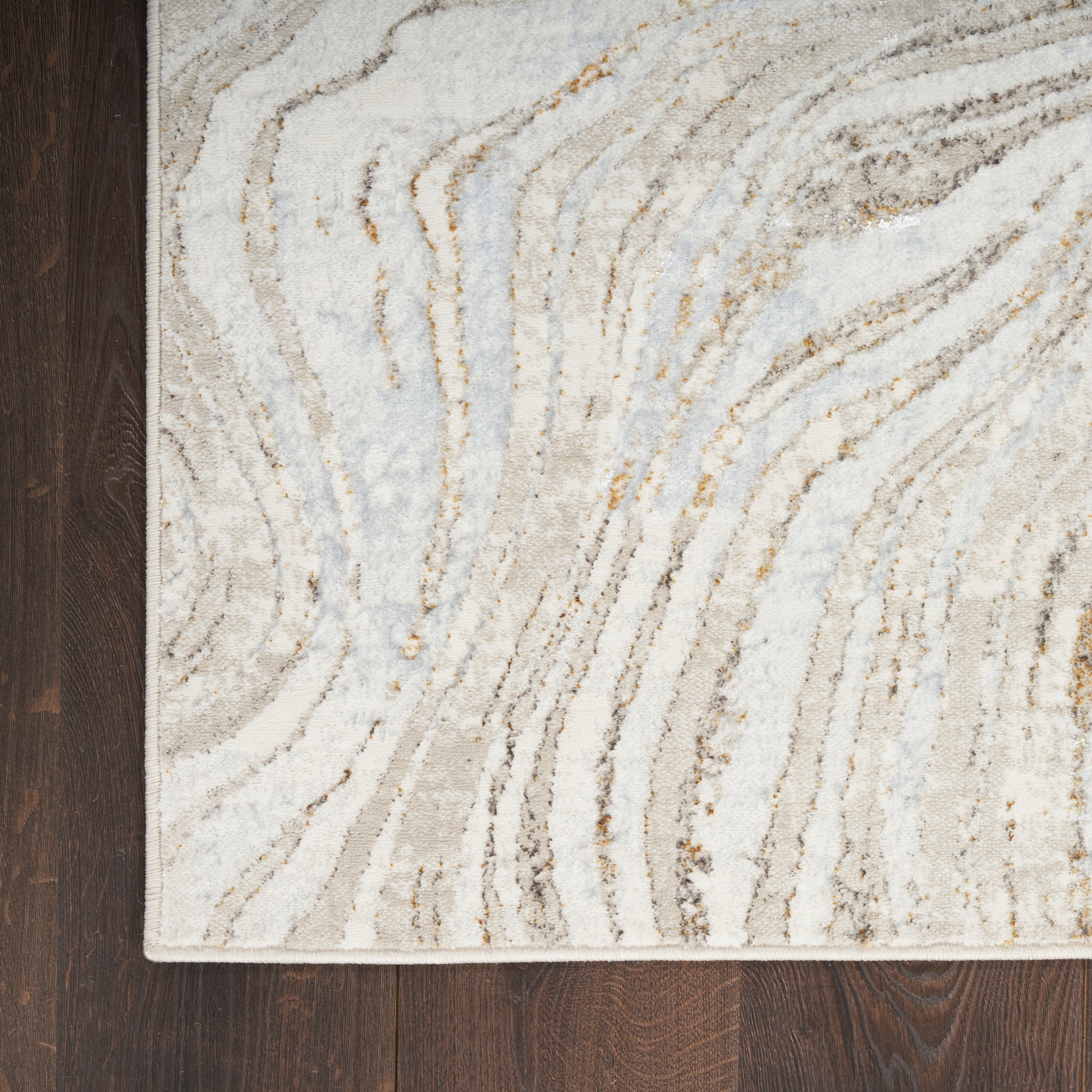Rectangular abstract runner rug with beige, cream, pale blue and tan wavy lines on dark wood floor.