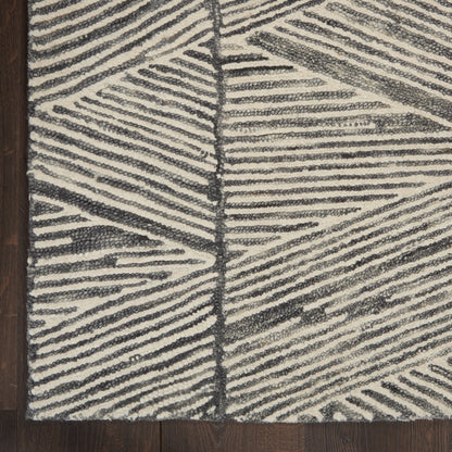 Rectangular ivory and charcoal rug with bold linear geometric pattern; plush textured pile on dark wood floor