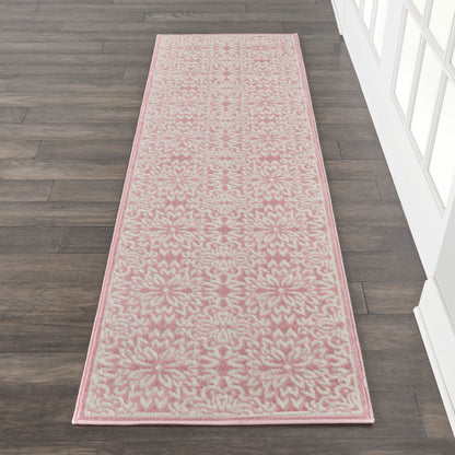 Pink floral patterned rug runner with cream accents, rectangular, placed on dark wood floor beside white paneled wall.