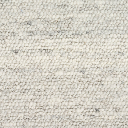 Cream boucle rug close-up with dense loop pile and subtle gray specks, soft textured surface.