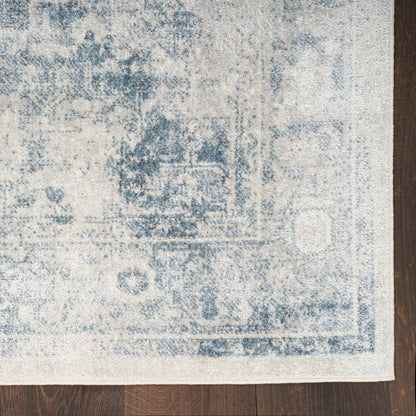 Distressed blue and ivory oriental rug with faded border on dark wood floor.