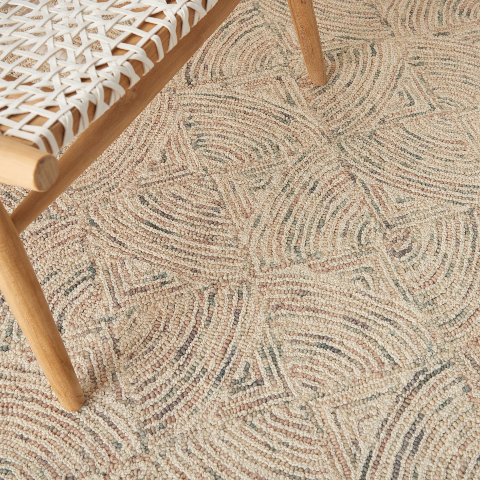 Light wood chair with a white woven lattice seat on a beige rug with circular swirl patterns.