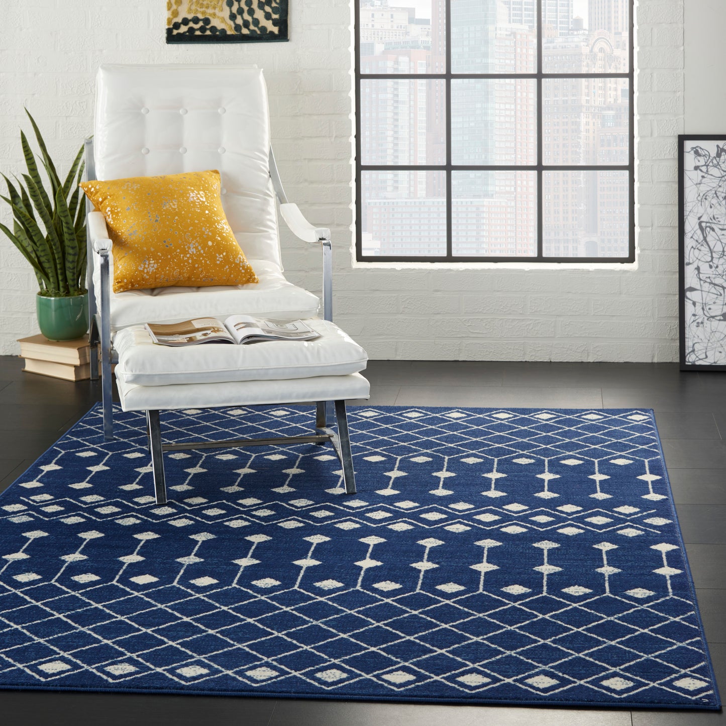 Navy blue geometric area rug with white lattice pattern beneath a white upholstered lounge chair and a mustard pillow.