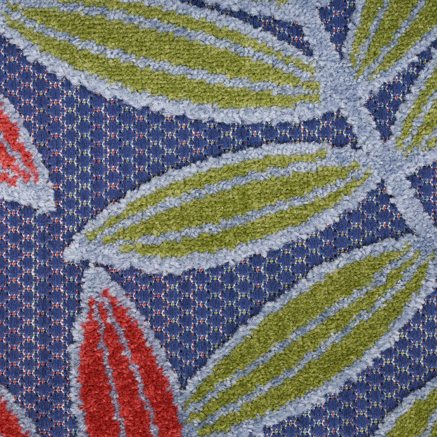 Close-up of a blue textured rug with lime-green leaf motifs outlined in pale blue and small red accents.