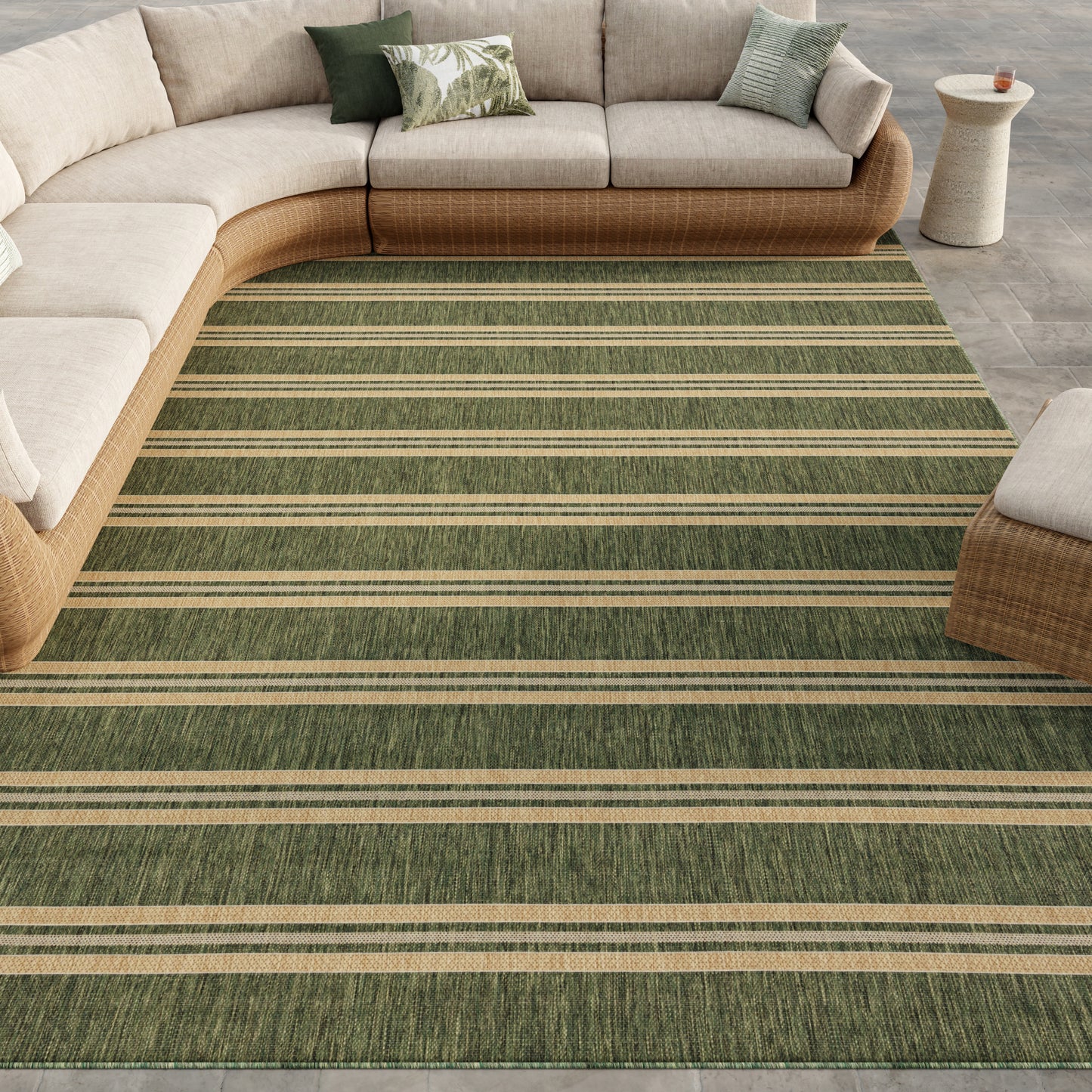 Green striped rug in a living room scene with a curved beige wicker sectional, light cushions, green accent pillows & a small side table.