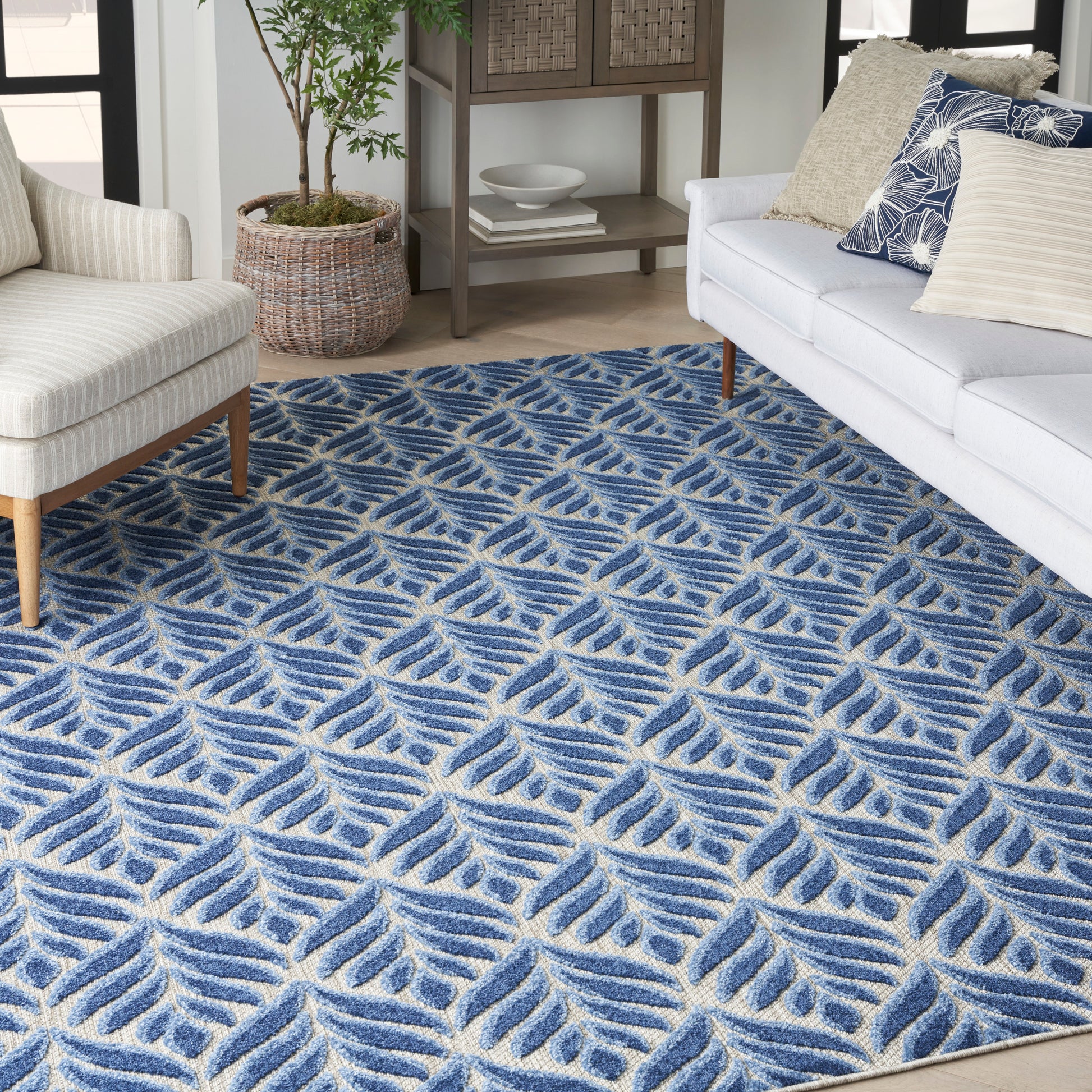 Blue leaf-pattern area rug anchors a cozy living room with beige armchair, gray sofa, and woven baskets.