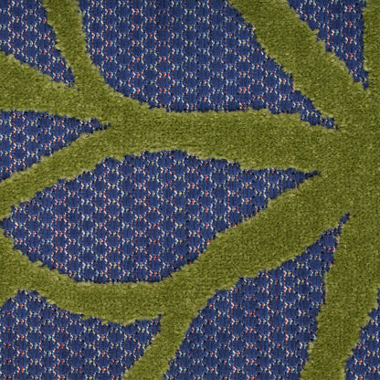 Close-up of blue textured rug with emerald-green abstract leaf pattern.