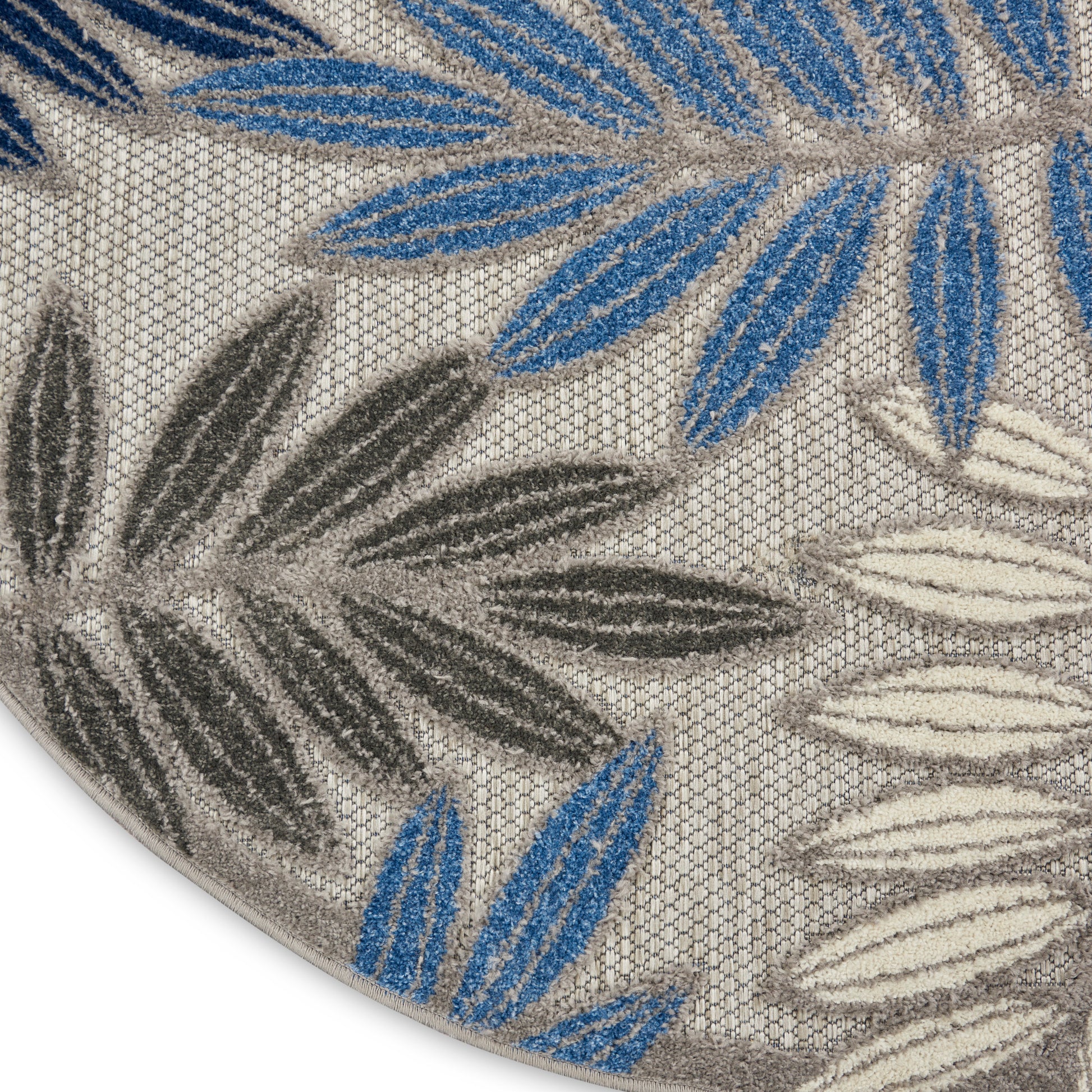 Round beige rug with blue, gray and ivory palm leaf motifs; textured looped pile.