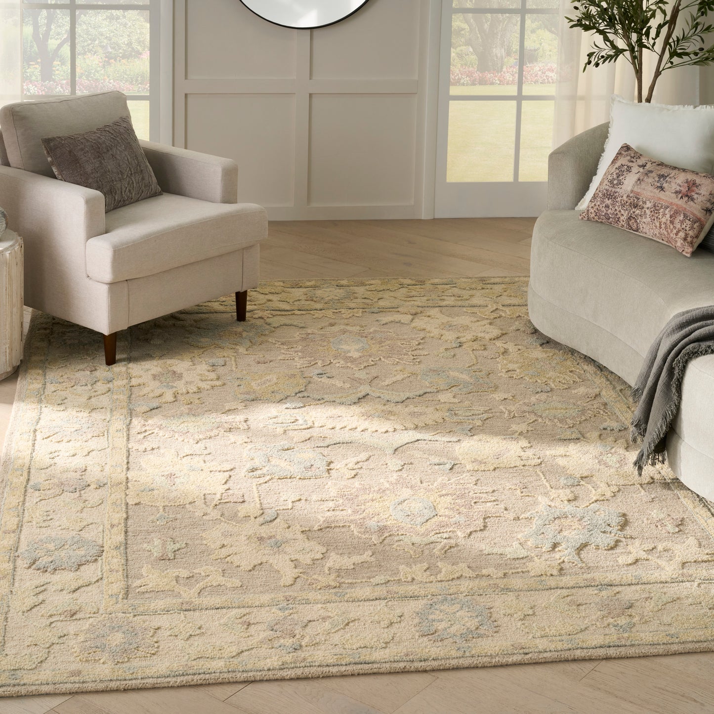 Light beige oriental-style area rug with blue-gray patterns in a cozy living room & neutral sofas.