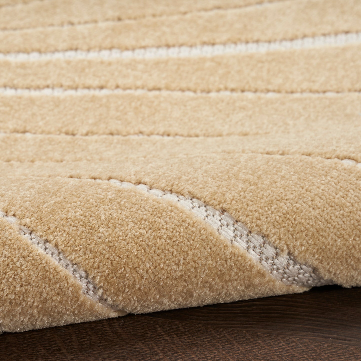Close-up of a beige outdoor runner rug with white wavy stripes on a dark wood floor.