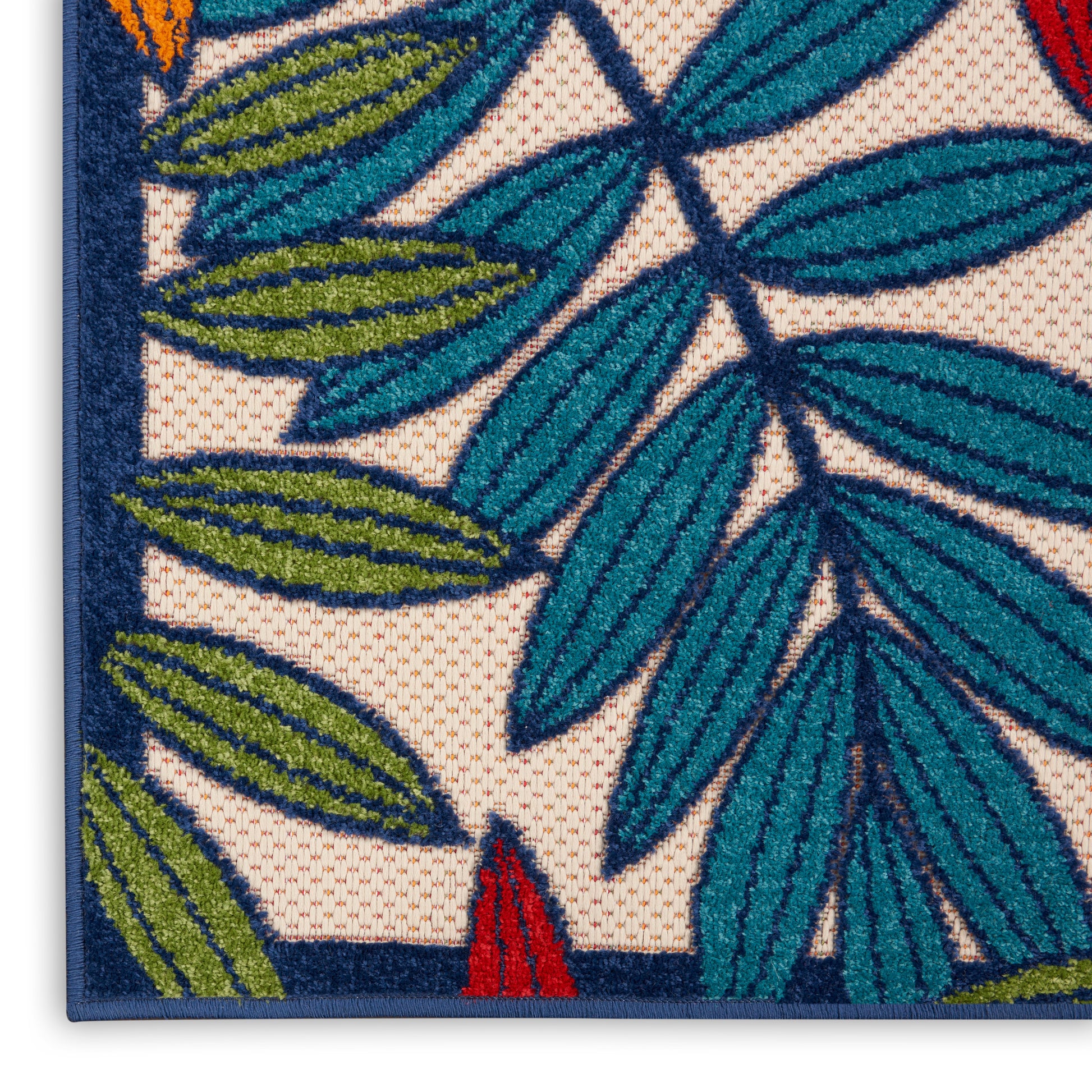 Corner of blue-bordered decorative rug with green palm-leaf border on beige background; red accent.