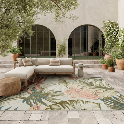 Outdoor beige linen sectional with wooden frame on a tropical floral rug, arched green-framed doors, potted plants.