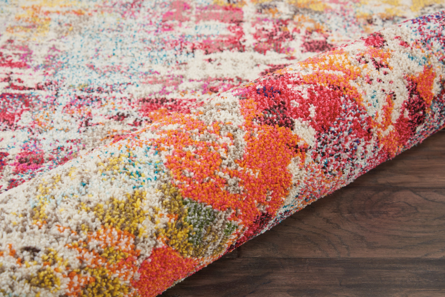 Rolled colorful shag rug with vivid pink, orange, yellow and blue pattern; cozy high-pile, modern living room decor.