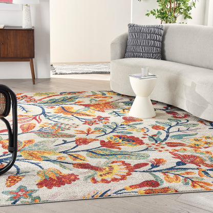 Bright living room with a vibrant floral rug in red, orange, teal on a light background, beige sofa and white pedestal table.