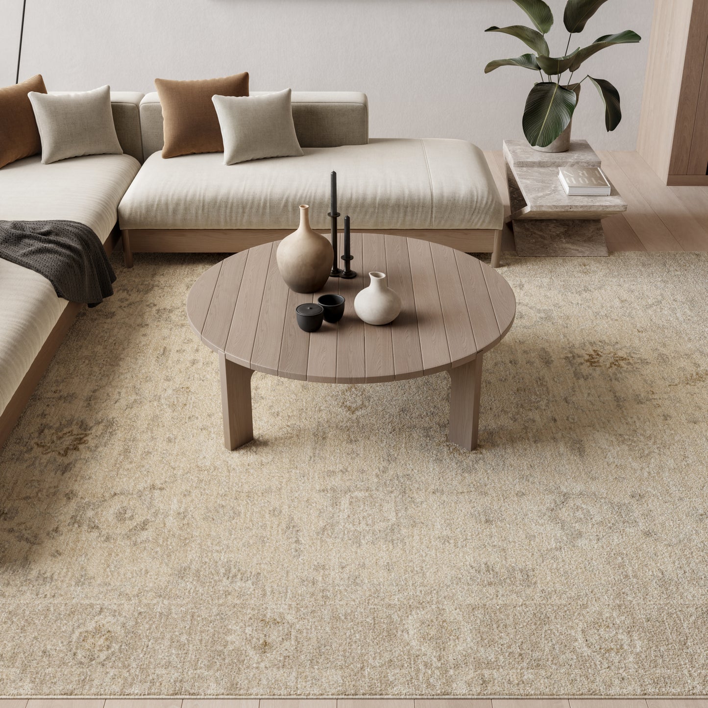 Round wooden coffee table on beige rug in a neutral Scandinavian living room with beige sectional and ceramic vases.