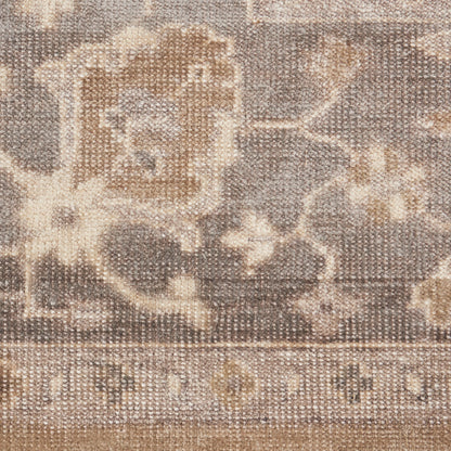 Close-up of a beige and taupe floral rug with woven texture and vintage oriental motifs.