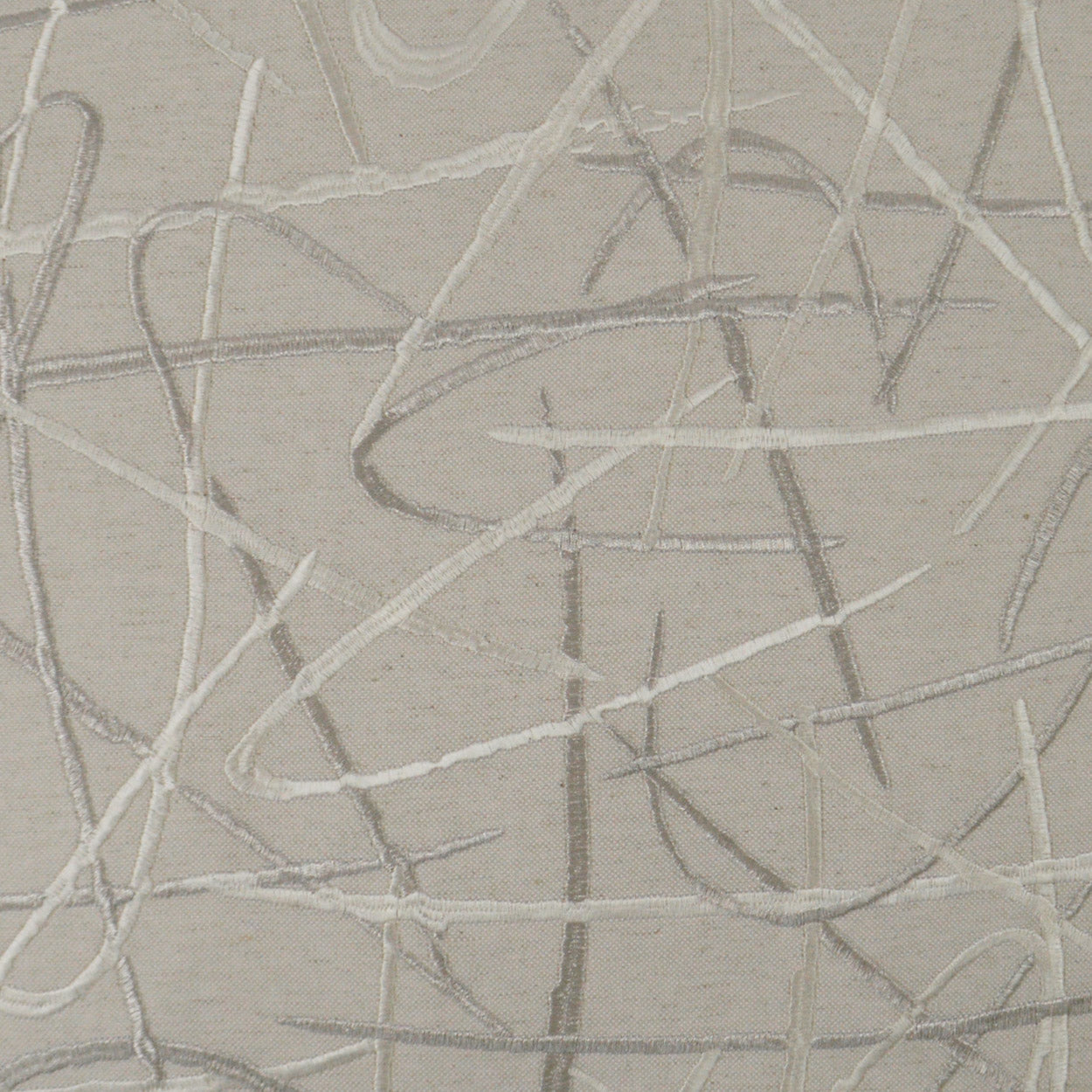 Beige fabric with random light-gray scribble lines creating an abstract, embroidered look.