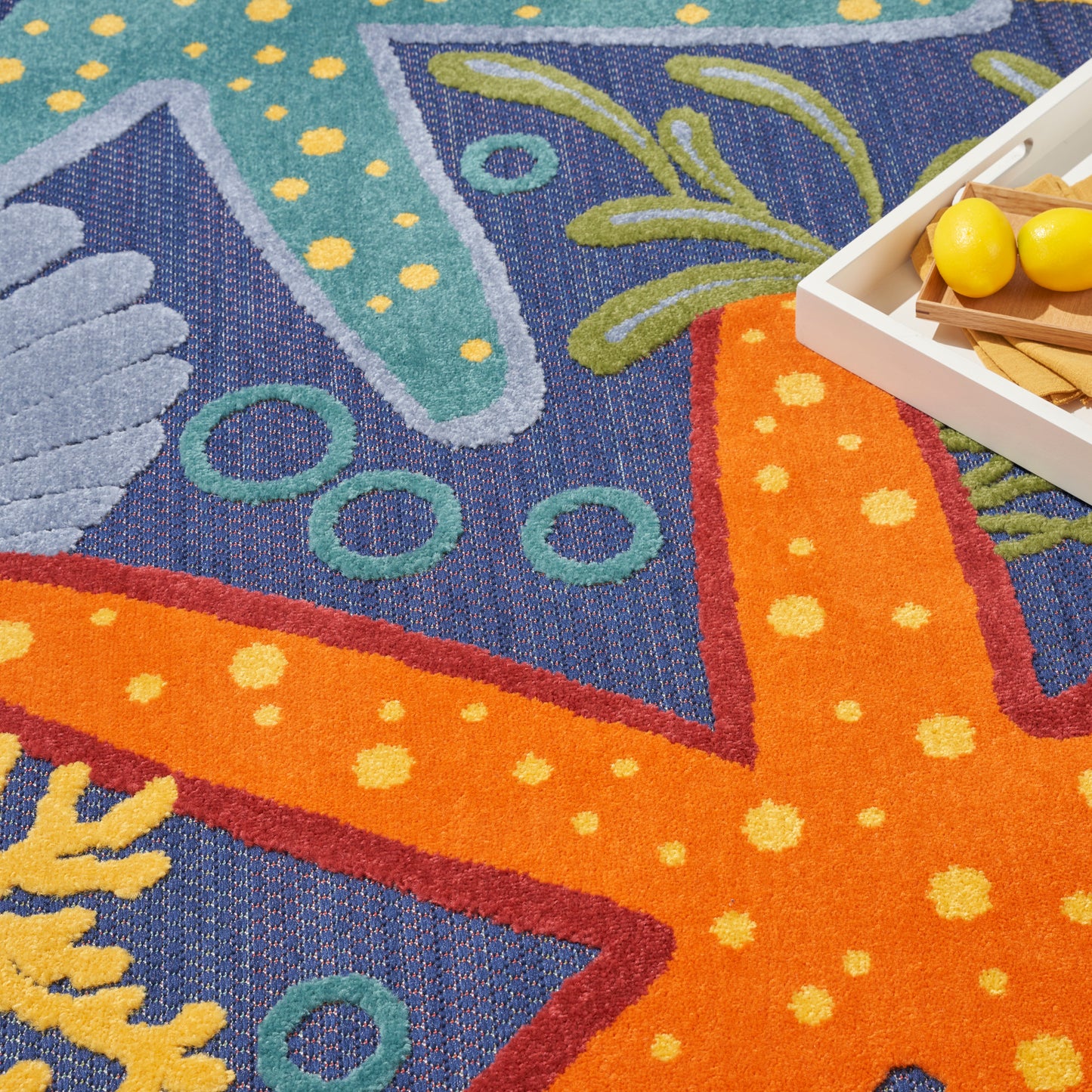 Vibrant woven outdoor rug with orange and blue geometric motifs, teal circles and yellow dots, 6' x 9'.