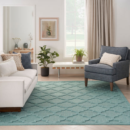 Bright living room with teal patterned rug, white sofa, blue-gray armchair, wooden coffee table and potted plants.