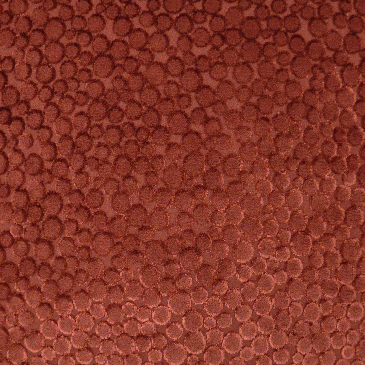 Close-up of reddish-brown pebble-grain leather texture with rounded bumps.