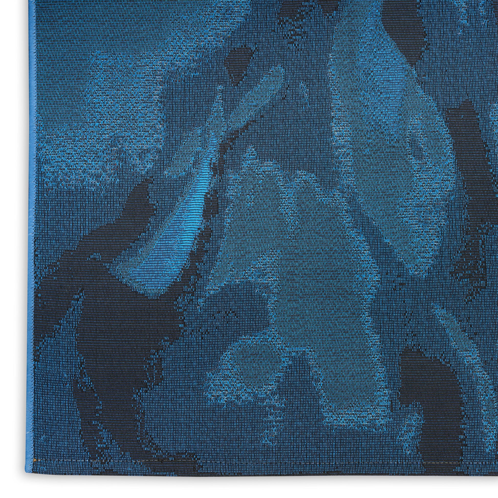 Blue jacquard tapestry rug with dark navy floral pattern on teal-blue background, dense woven texture.