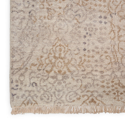 Beige and gray patterned rug with intricate floral motifs and a fringed edge.