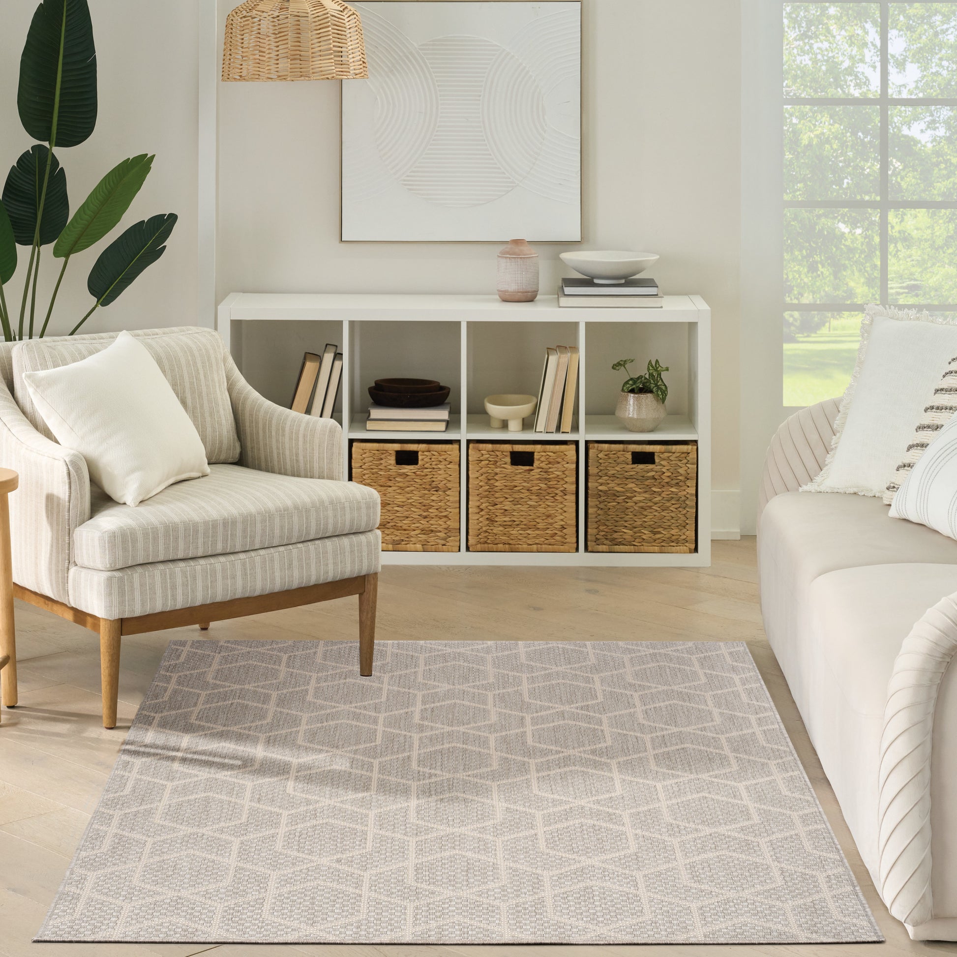 Cozy neutral living room with a cream armchair, white cubby storage with woven baskets, a geometric rug (5' x 7'), and a large window.