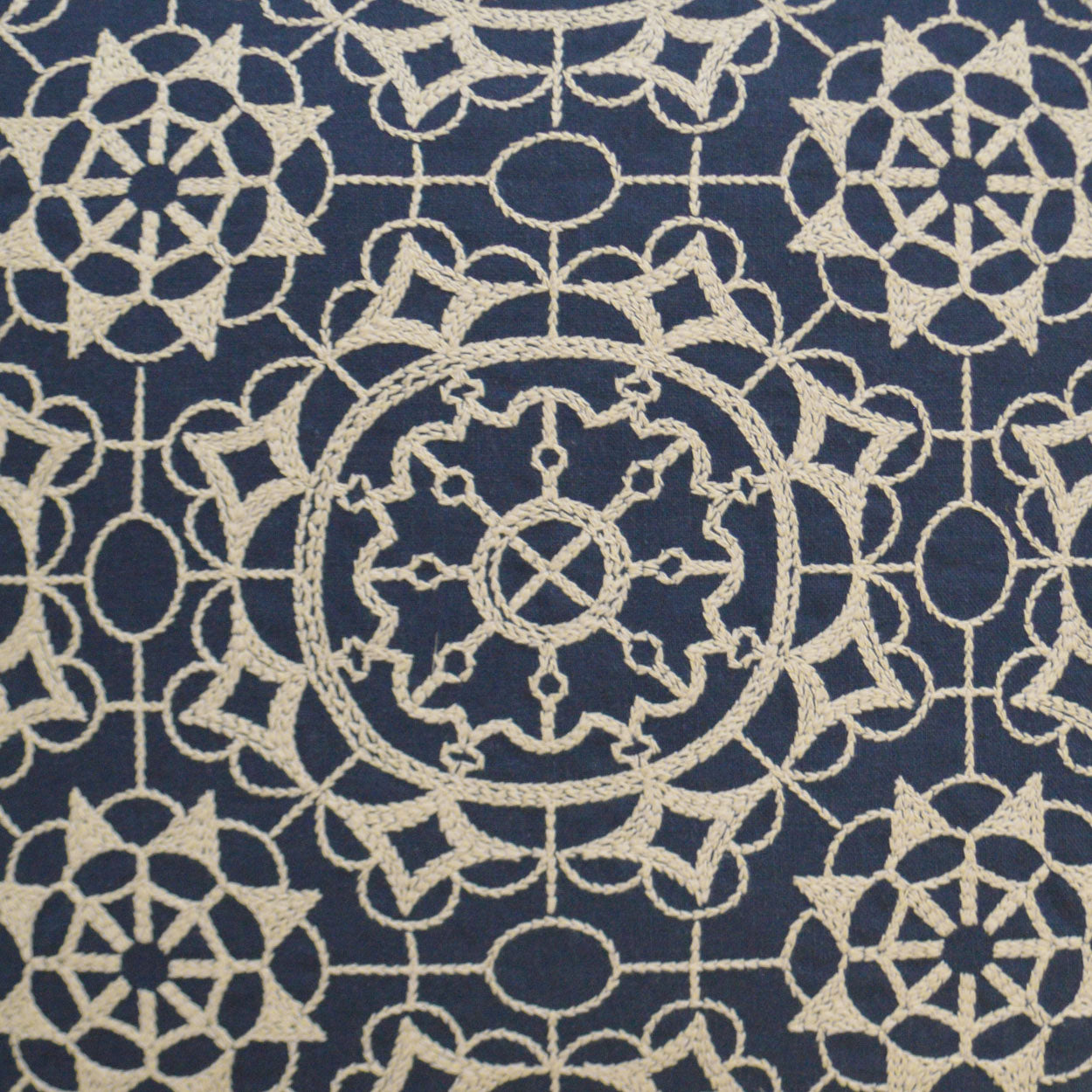 Cream lace-like geometric pattern on navy fabric with circular medallions; decorative textile for upholstery.