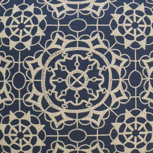 Cream lace-like geometric pattern on navy fabric with circular medallions; decorative textile for upholstery.