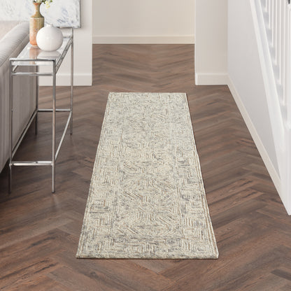 Beige geometric runner rug on dark herringbone floor beside a metal console table with vases.