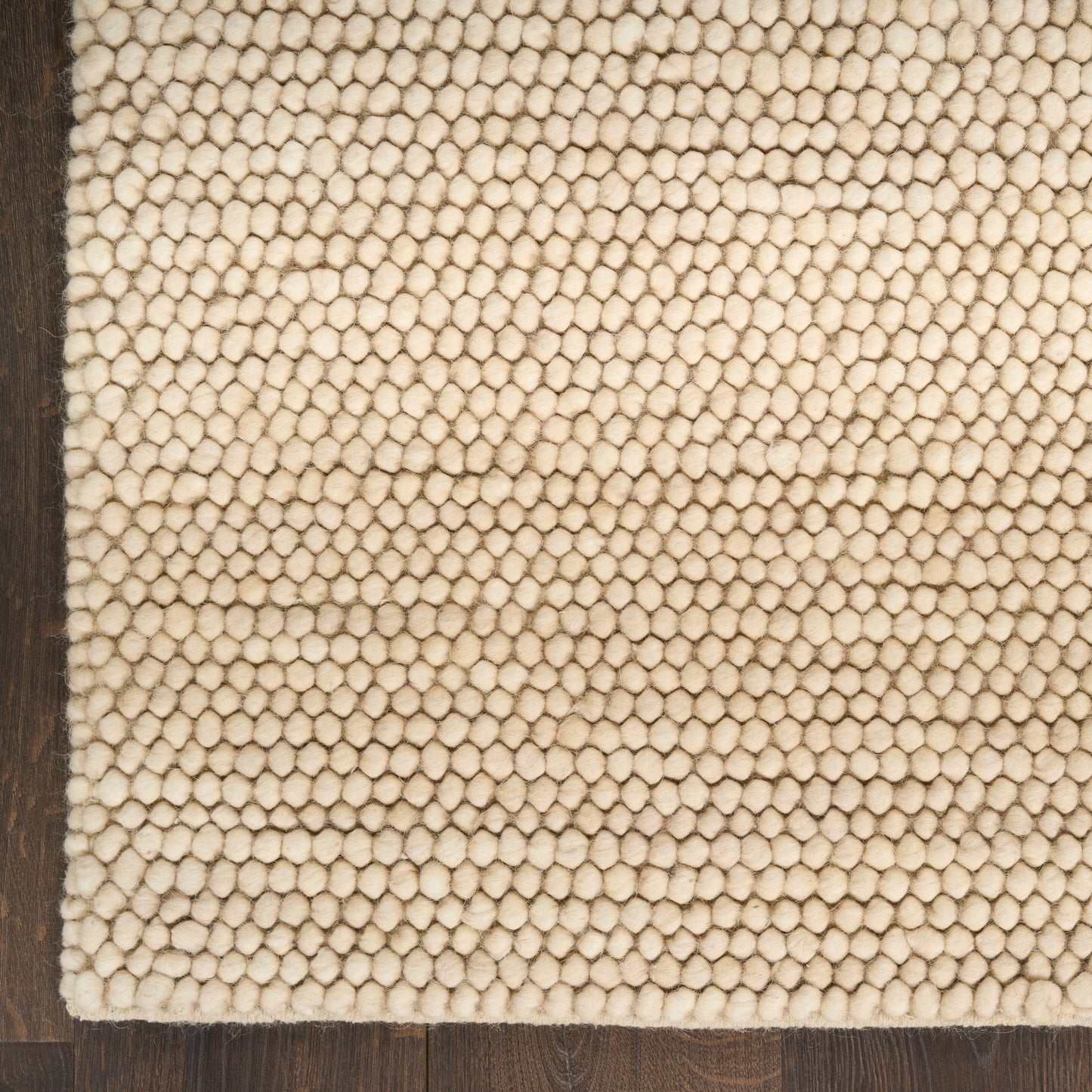 Beige loop-pile rug with dense textured surface on dark wood floor; cozy, modern rustic style.