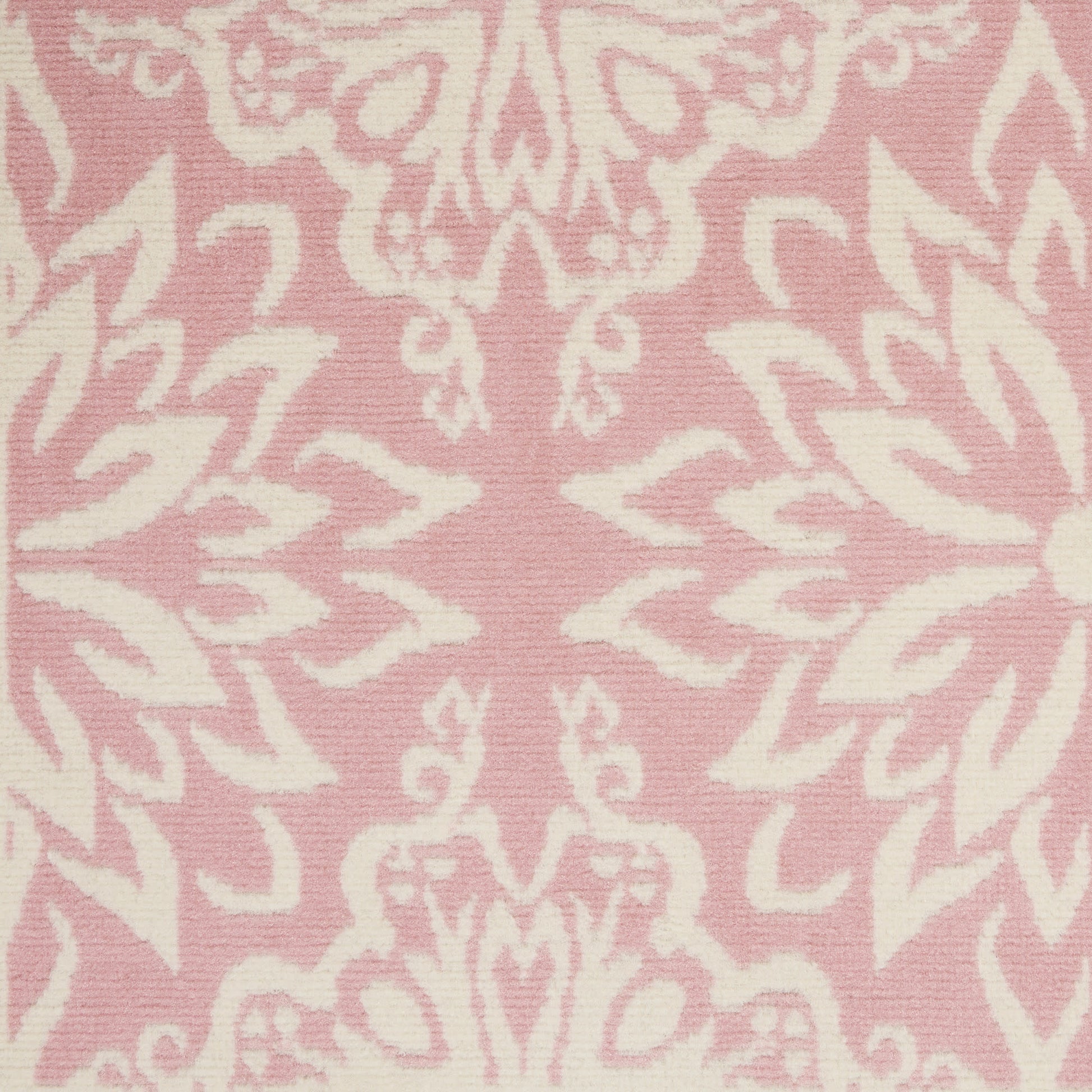 Pink damask rug with white ornate floral motifs in a repeating decorative pattern.