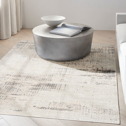 Round gray concrete coffee table with white top, a magazine and bowl, on a light beige patterned rug in a modern living room.