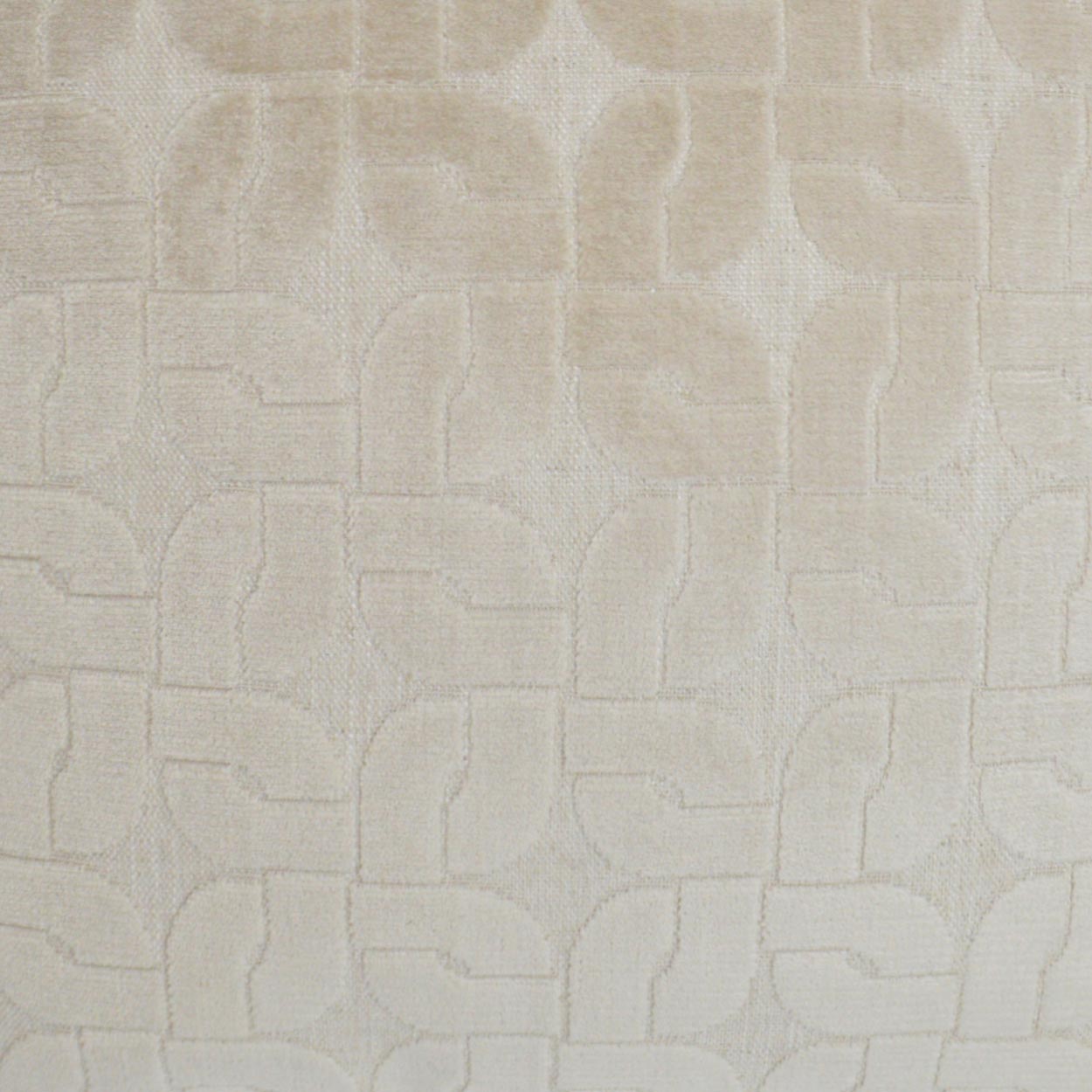 Cream-beige textured fabric with a subtle raised geometric pattern of interlocking curved blocks.