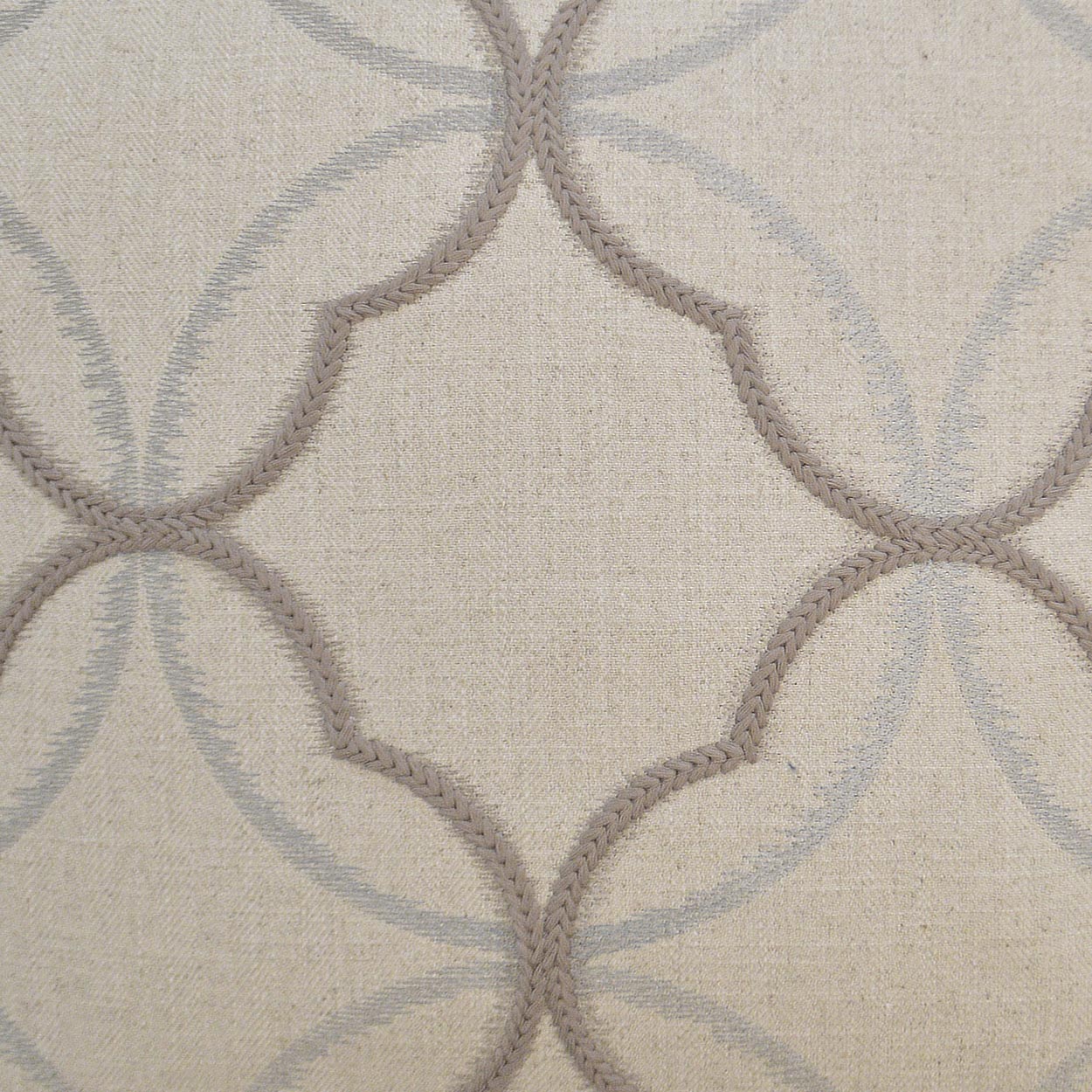Beige woven fabric with taupe rope-outline quatrefoil motifs and pale blue circular arches.