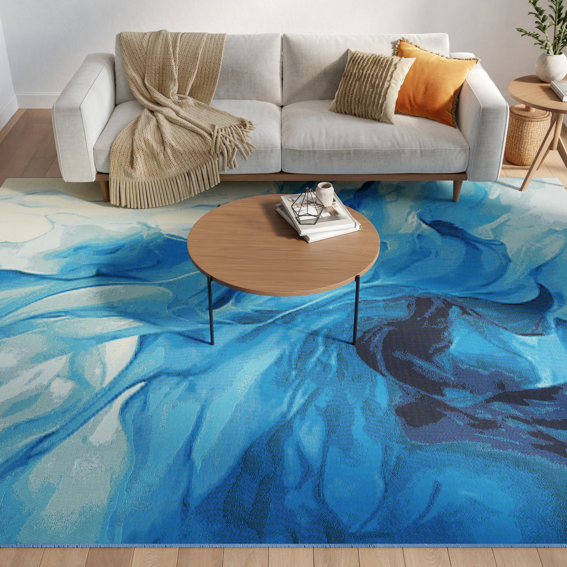 Blue abstract rug in a living room featuring a light gray sofa, beige throw & orange cushion; round wooden coffee table with books.