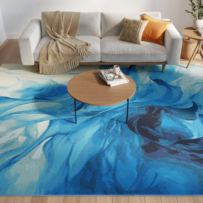 Blue abstract rug in a living room featuring a light gray sofa, beige throw & orange cushion; round wooden coffee table with books.