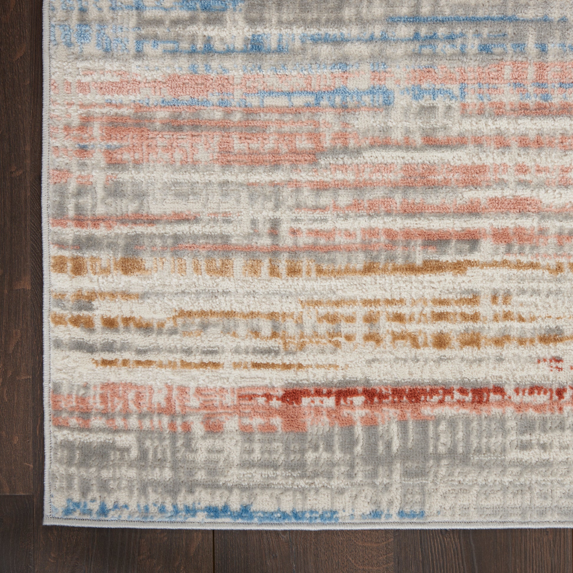 Rectangular abstract area rug with a gray base and irregular blue, orange, tan, and red bands on dark wood floor.