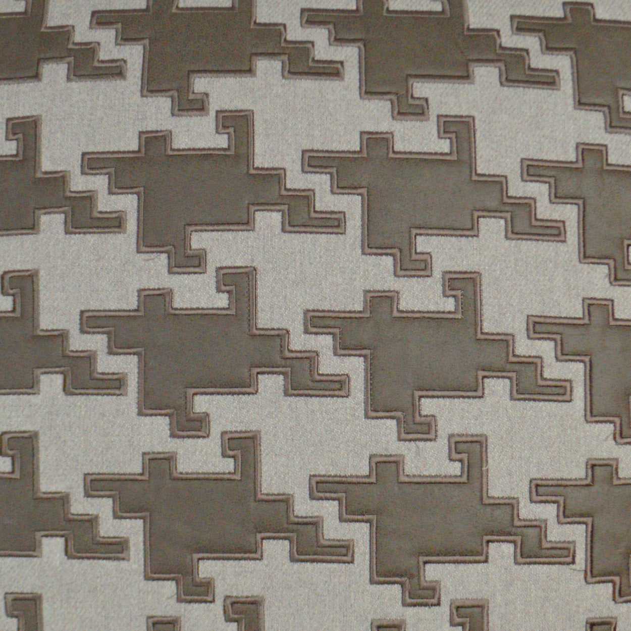 Beige fabric with taupe geometric stepped pattern; interlocking shapes, ideal for upholstery.