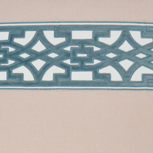 Teal-blue geometric lattice border across beige fabric; decorative interlocking pattern with a modern cutwork look.