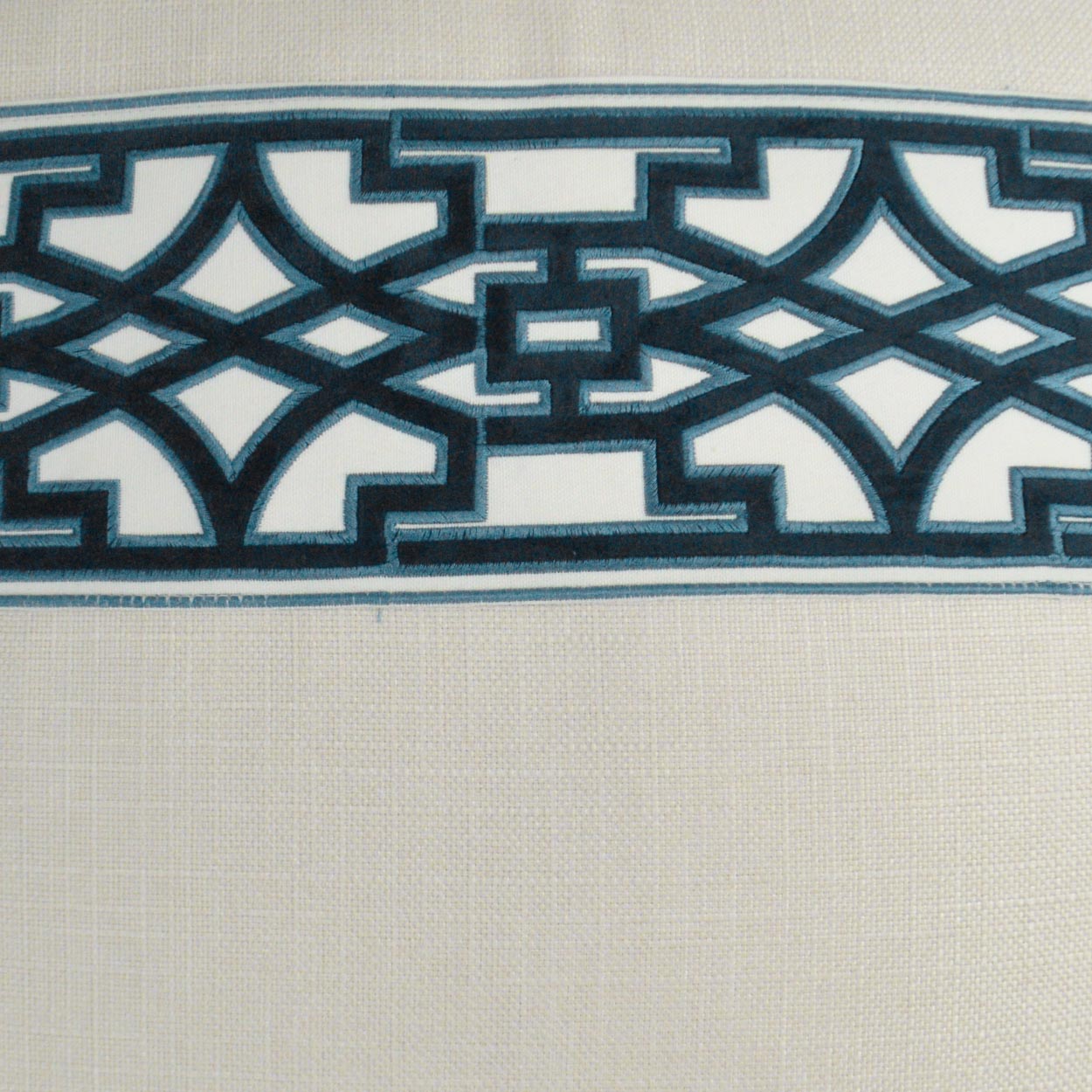 Cream woven fabric with teal geometric lattice border and navy accents.