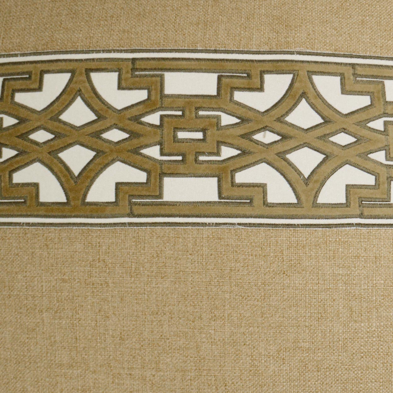Beige textured fabric with a wide gold metallic Greek-key lattice band across.