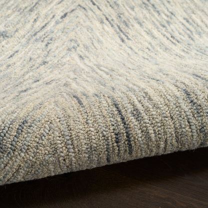 Close-up of a grey-blue loop-pile rug with a subtle, wavy stripe pattern on dark wood floor.