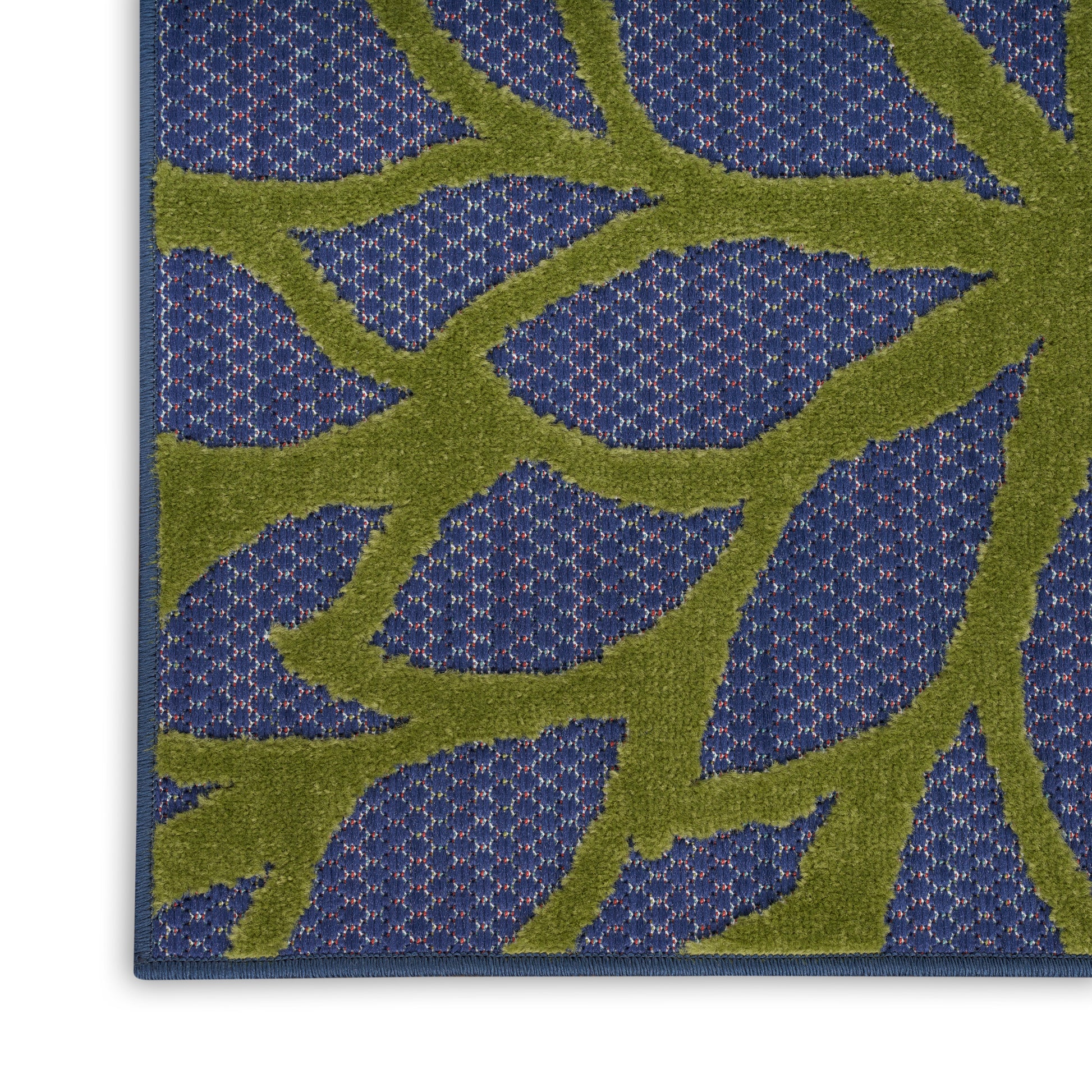Blue rug with lime-green botanical branch motif on a dotted background; decorative floor mat
