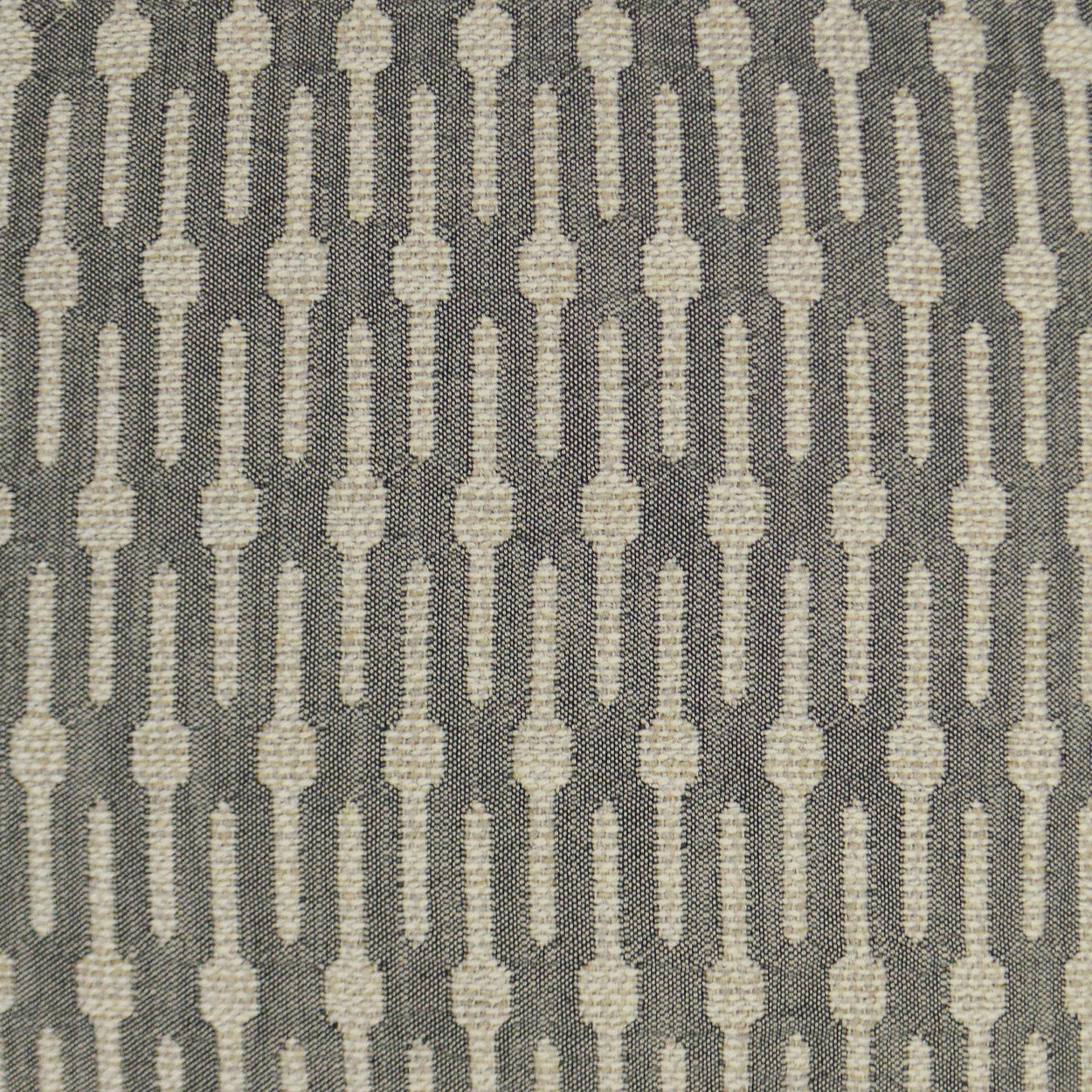 Cream elongated oval motif in vertical rows on charcoal gray woven fabric; geometric retro pattern.
