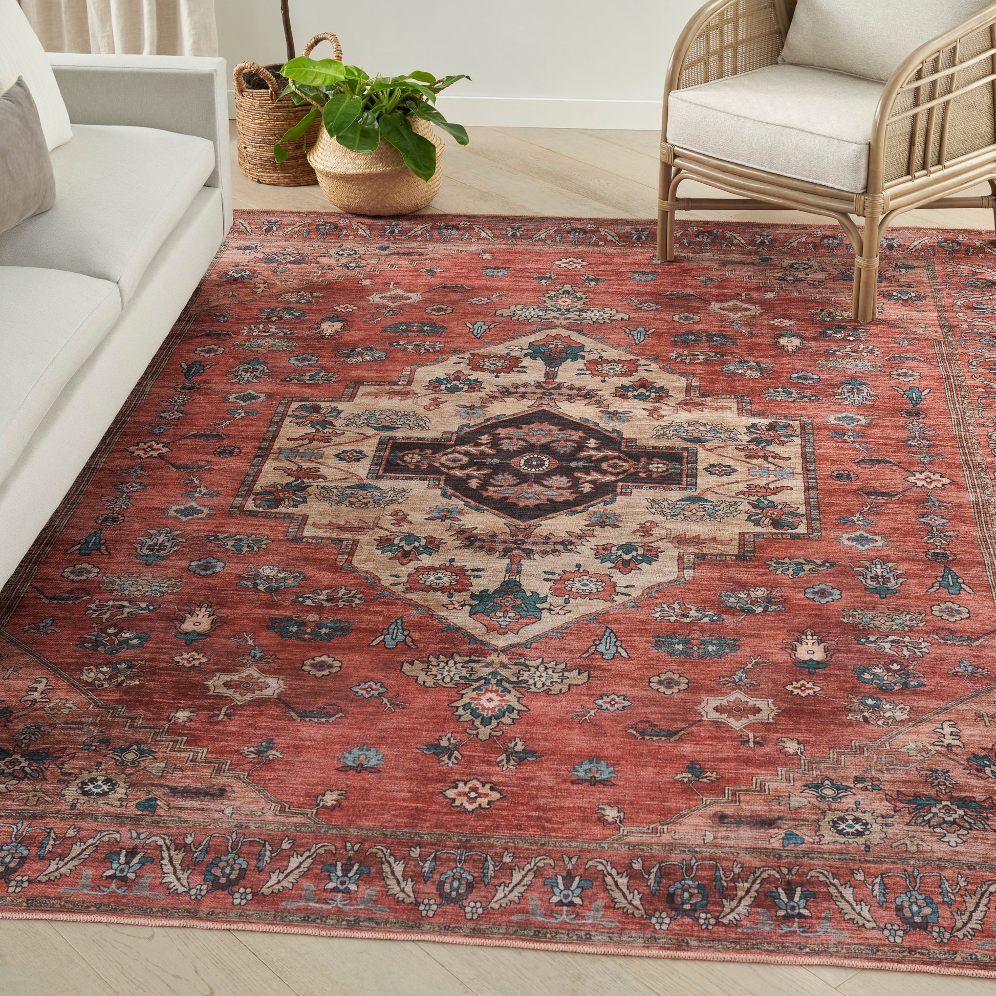 Red Persian-style area rug with ivory central medallion and blue accents, in a living room with cream sofa.
