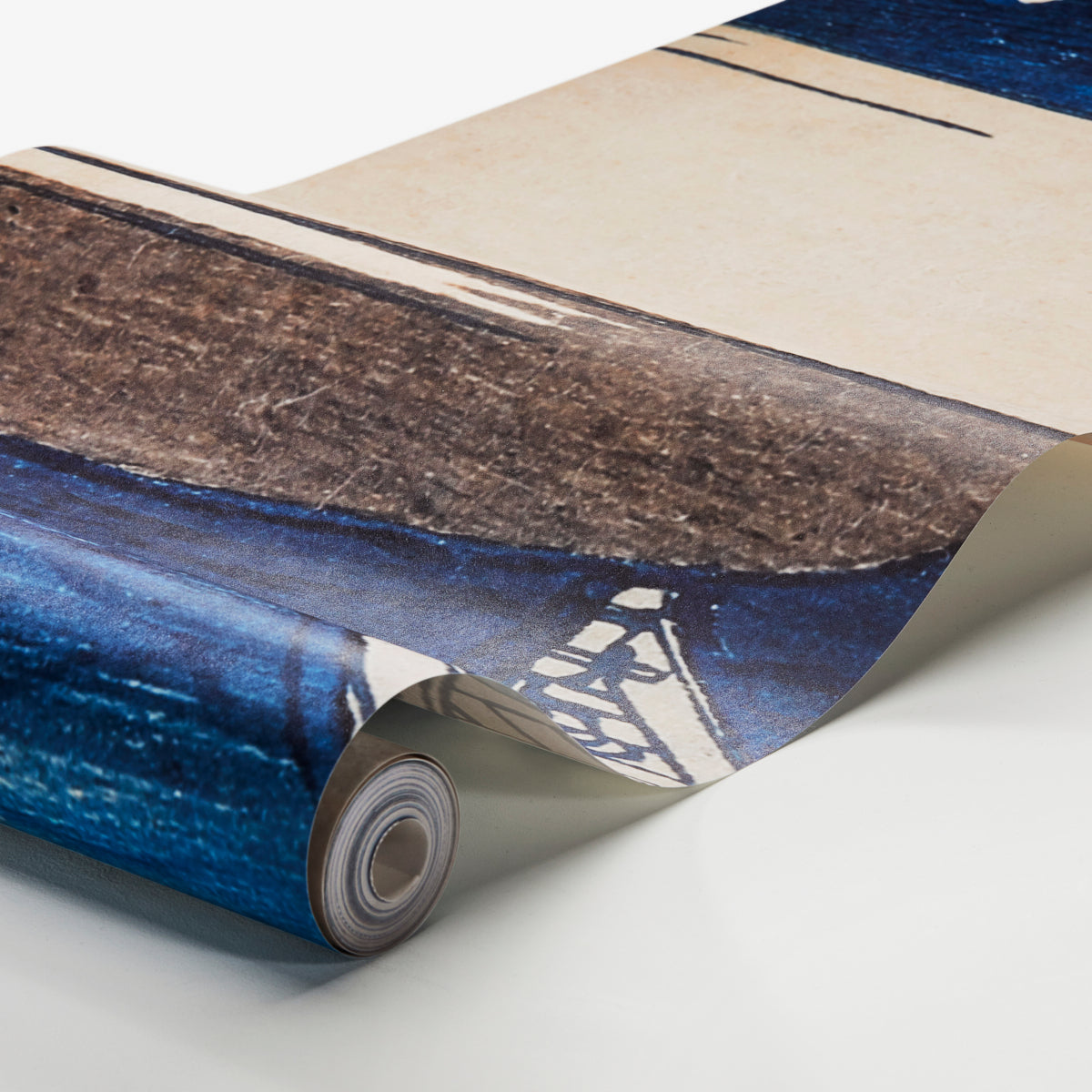 Rolled wall mural with blue ocean hues and beige sand tones, curling at the edge.
