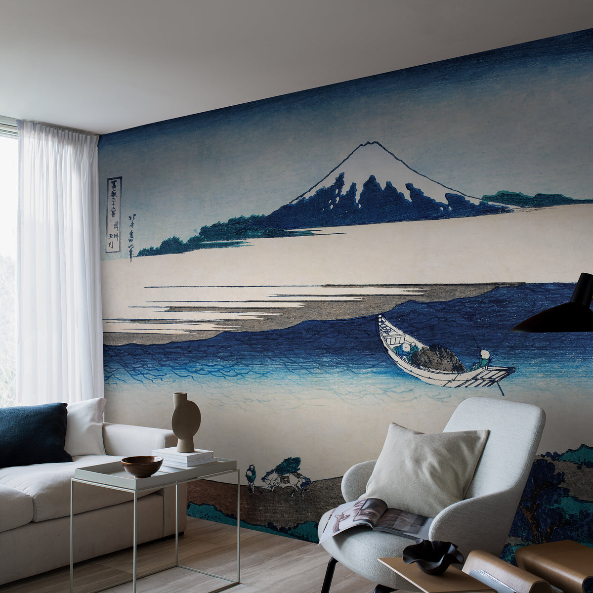 Living room with a Mt. Fuji blue-water mural, white sofa, neutral cushions, and a minimalist glass side table.